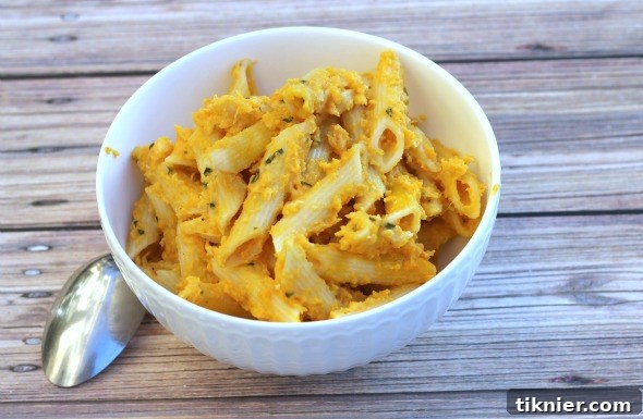 Close-up of a bowl of butternut squash cream sauce and penne pasta, garnished and ready to eat
