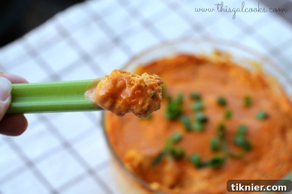 Buffalo Chicken Dip, garnished with green onions and served with celery and chips.