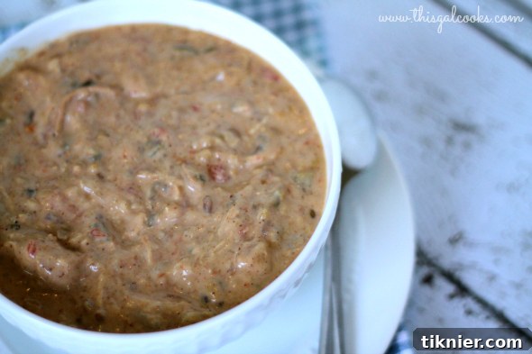 A large bowl of Mexican Style Crockpot Creamy Chicken Soup garnished with fresh herbs and a slice of lime.