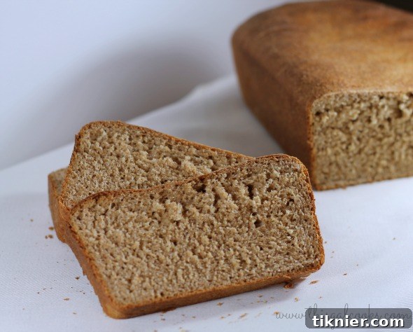 Freshly baked 100% whole wheat bread cooling on a rack, ready to be sliced.