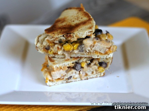 Close-up of a Zesty Flatbread Melt, showing the melted cheese and colorful ingredients peeking out.