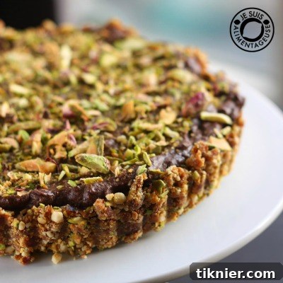 A decadent Vegan Pistachio Chocolate Cheesecake, featuring a rich, creamy filling and a wholesome cashew-date crust, garnished with pistachios and chocolate.
