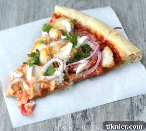 Closeup of a slice of Chicken Enchilada Pizza, showing layers of toppings.