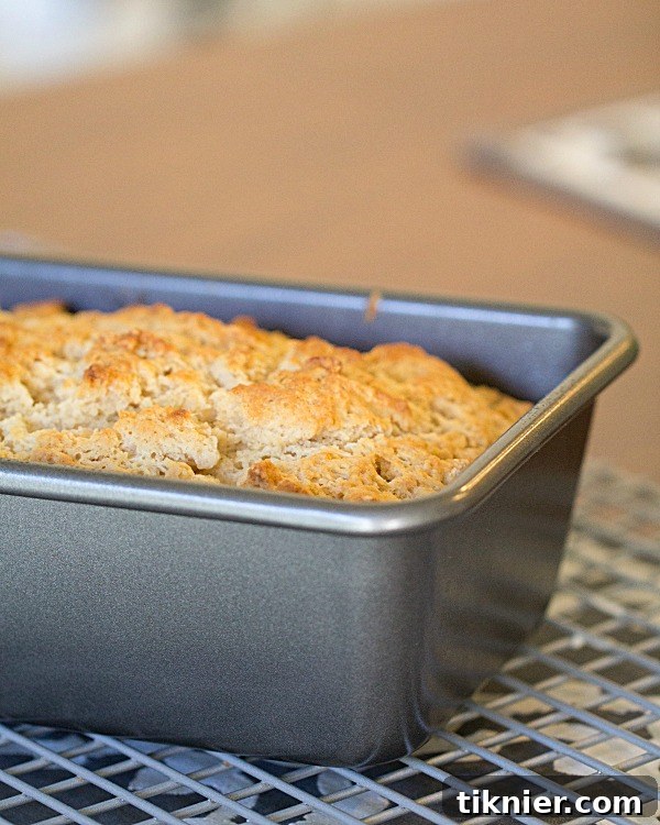 Slices of Beer Batter Bread on a wooden cutting board with a bread knife, ready to be served