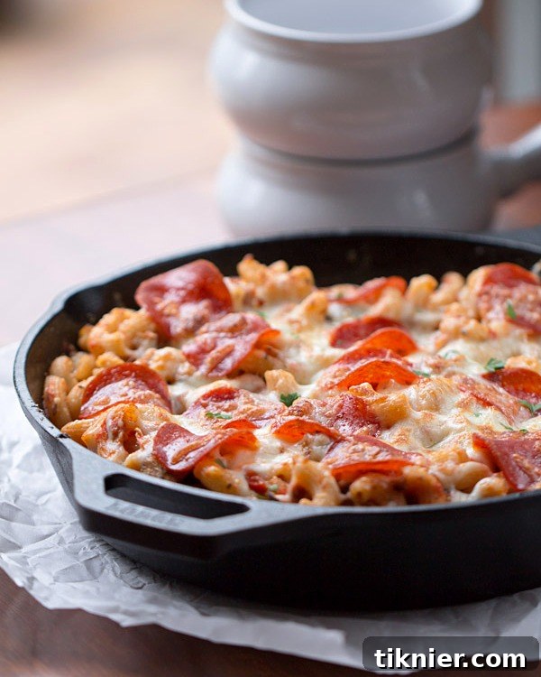 A close-up of the gooey, cheesy interior of the Skillet Pizza Pasta Bake, highlighting the pasta, sausage, and vegetables.