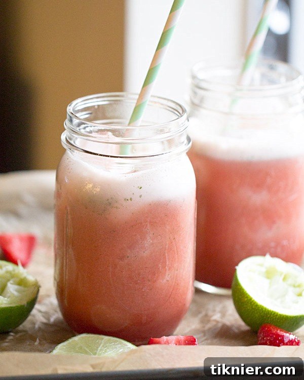 Side view of a Strawberry Lime Mint Spritzer, showing layers of ice, liquid, and garnishes