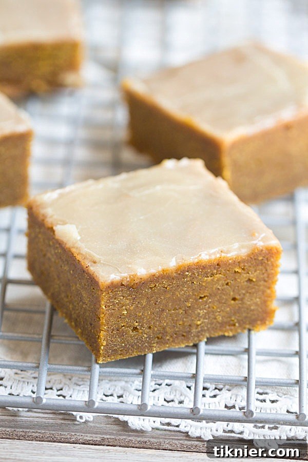 Close-up of a stack of freshly baked Pumpkin Spice Bars, topped with glistening Bourbon Butter Glaze, ready for serving.