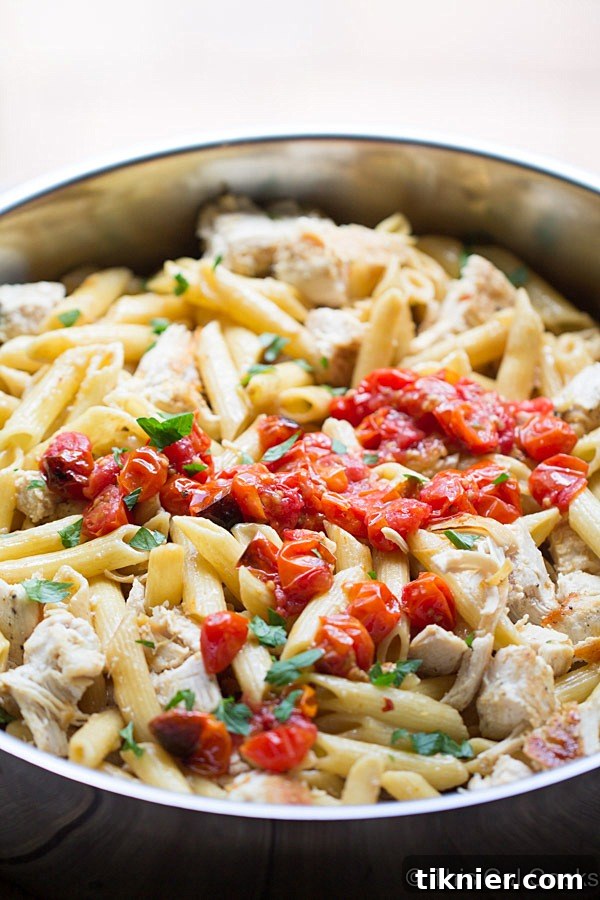 A large skillet filled with creamy One Pan Chicken Pasta with Chardonnay Wine Sauce, garnished with fresh parsley.