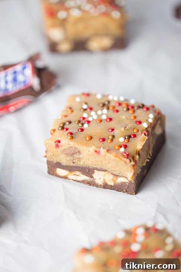 Sliced Snickers Chocolate Peanut Butter Pumpkin Fudge showing the soft, creamy texture and generous chunks of Snickers inside.