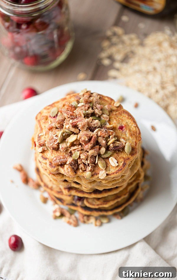 Healthier dairy free Cranberry Pumpkin Pancakes topped with streusel and syrup.