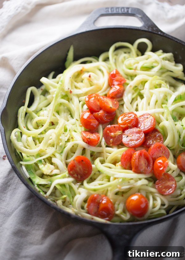 Close-up of freshly cooked zucchini noodles with roasted tomatoes and white wine sauce.