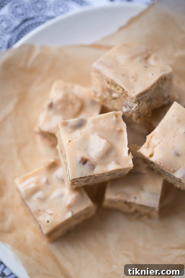 Close-up of a square of Butter Pecan Fudge, showcasing its smooth texture and visible pieces of chopped pecans and graham crackers.