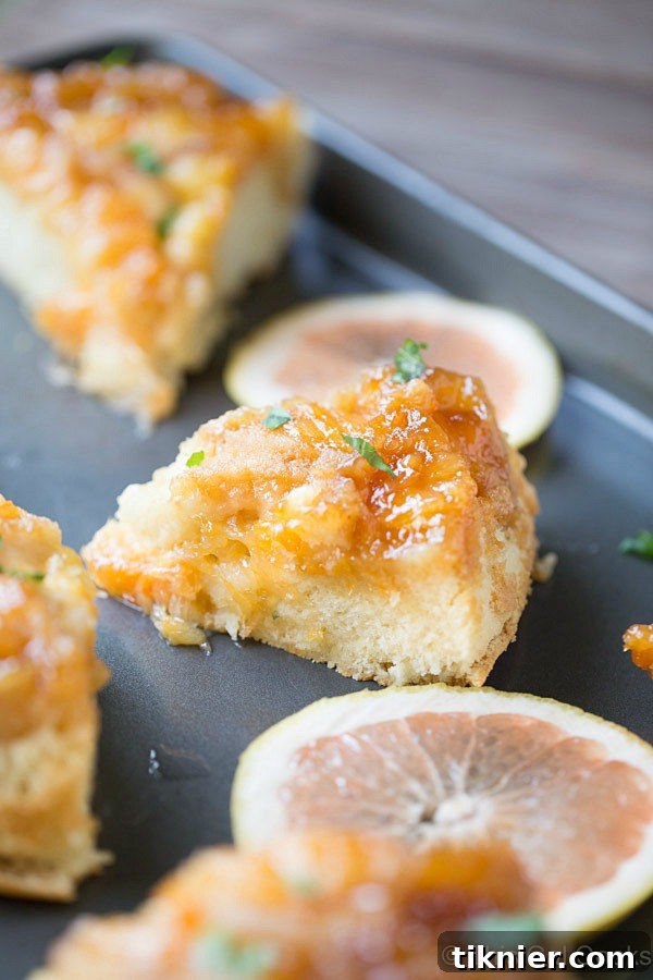 Caramelized Grapefruit Upside Down Cake 6 A generous slice of Grapefruit Upside Down Cake on a white plate, ready to be enjoyed. The rich color of the grapefruit and the golden cake are visible.