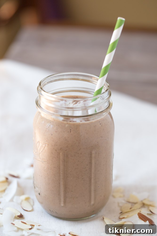 A beautifully presented Almond Joy Protein Shake, topped with a generous sprinkle of coconut flakes, ready to be enjoyed as a satisfying vegan meal replacement.