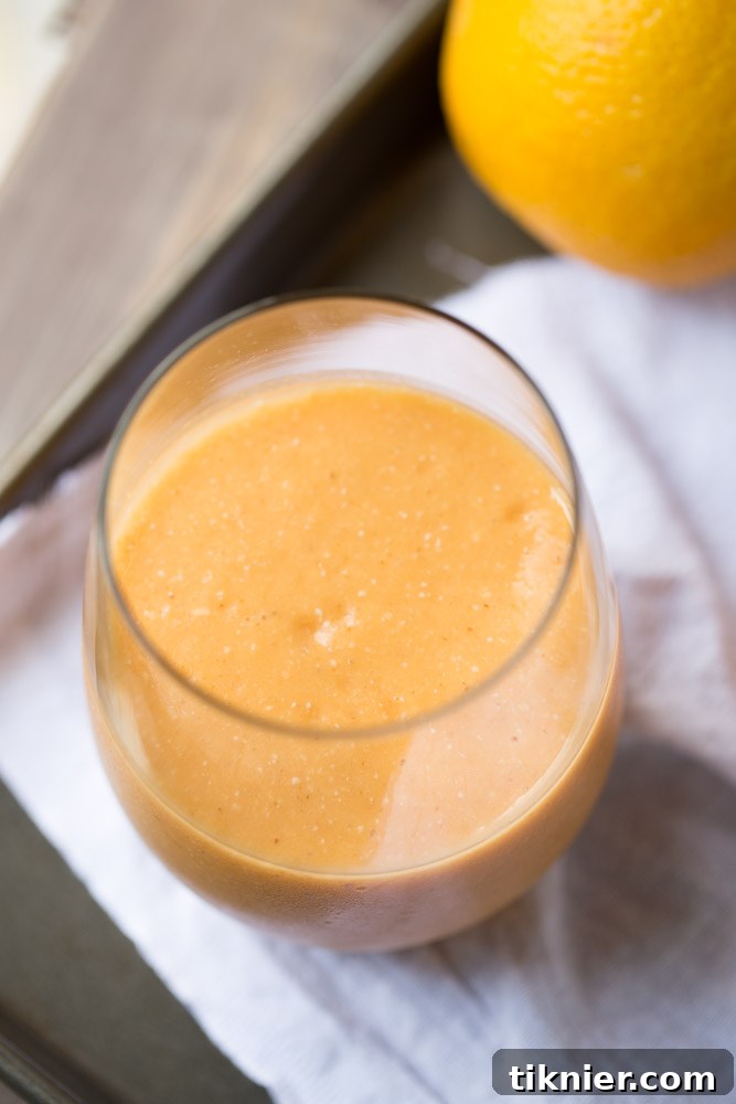 Orange Carrot Protein Smoothie garnished with fresh orange slices and mint