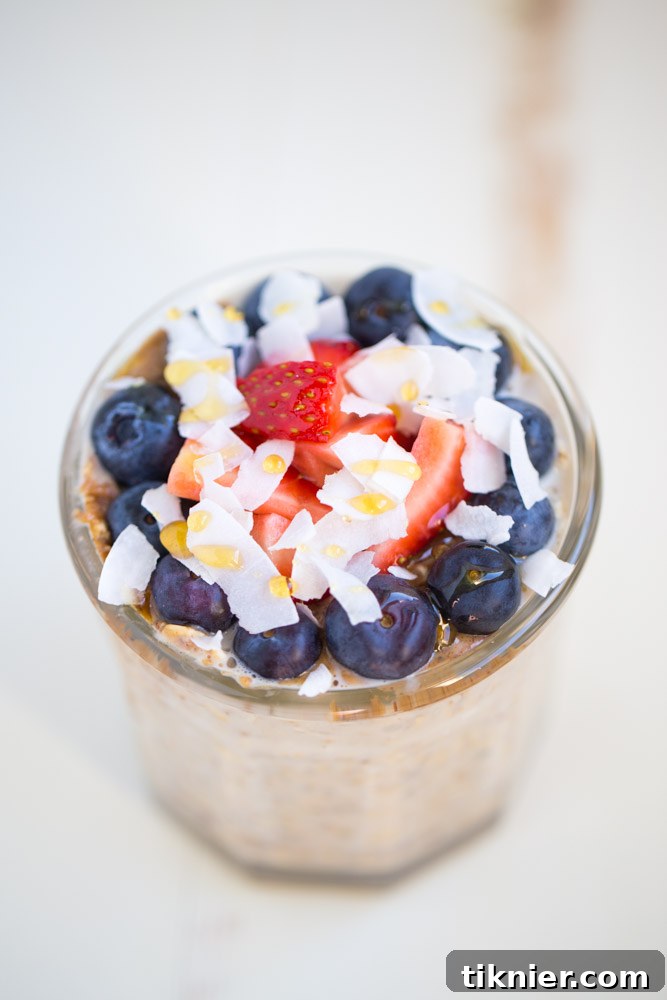 Beautifully layered overnight oatmeal parfait with fresh berries, flax, and almond butter, ready for a healthy breakfast.