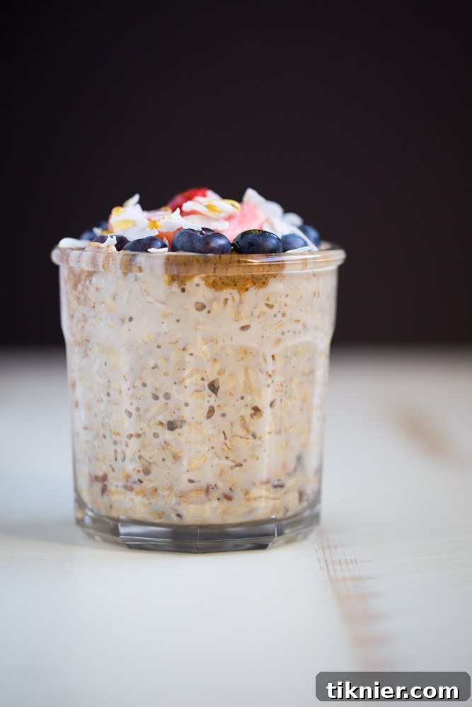 A close-up shot of the raw ingredients for overnight oatmeal parfait including oats, berries, flax seeds, and almond butter.