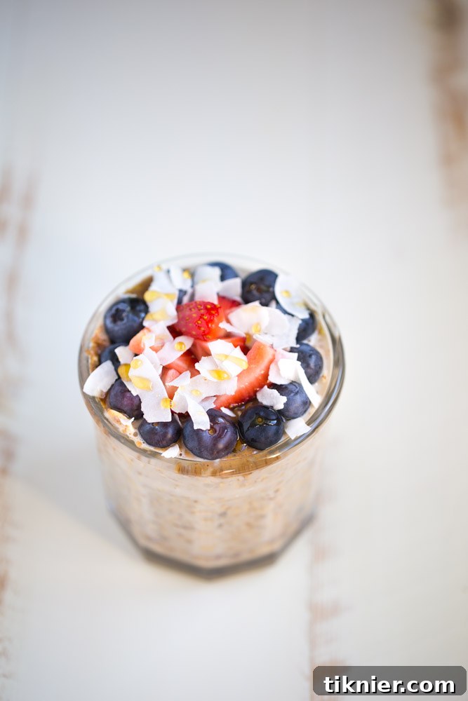Overhead view of a beautiful Overnight Oatmeal Parfait with berries, oats, and coconut flakes.