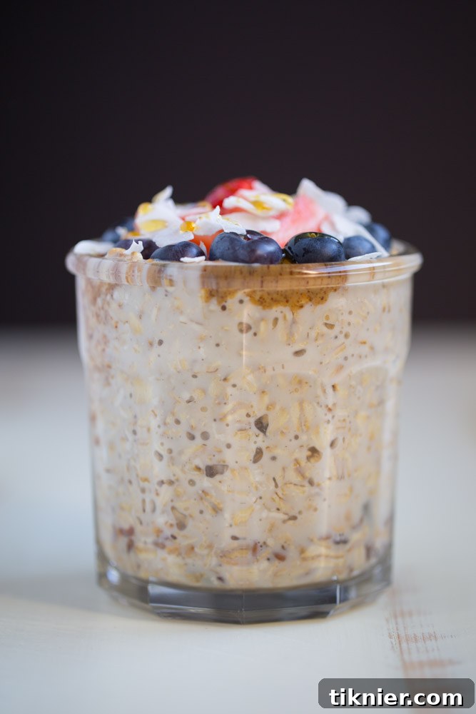 Close-up of a spoon digging into a creamy, berry-filled Overnight Oatmeal Parfait.