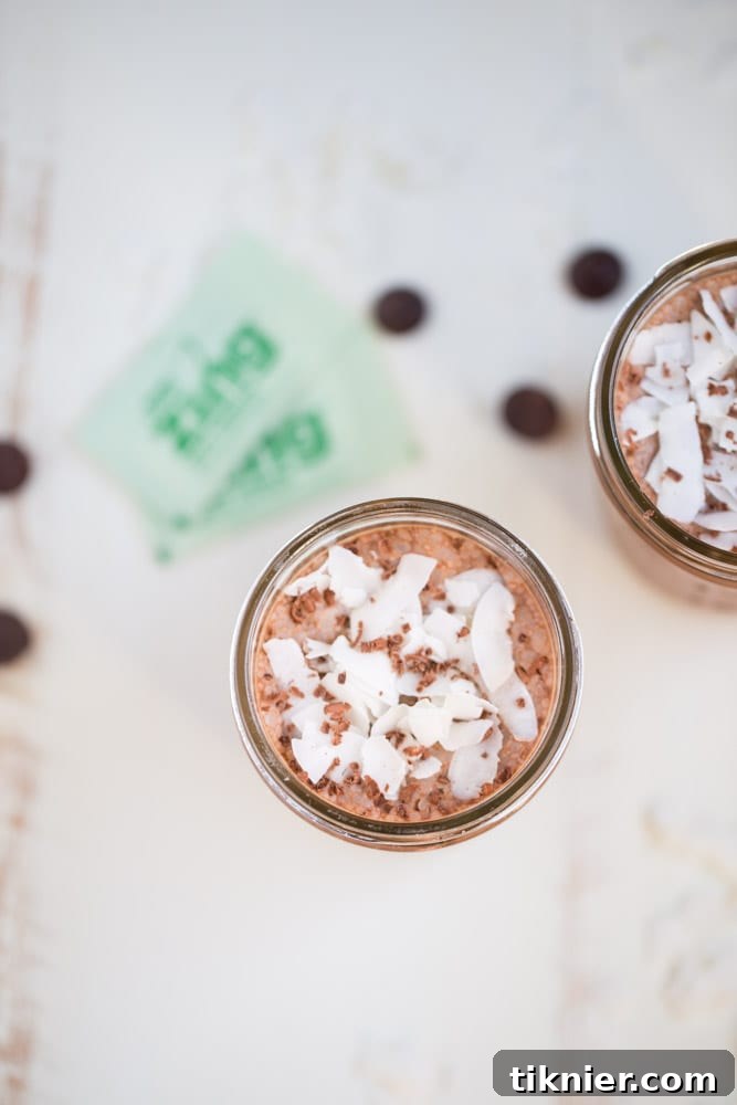 Two glasses of Coconut Mocha Coffee Smoothie with shredded coconut topping, set on a rustic wooden surface.