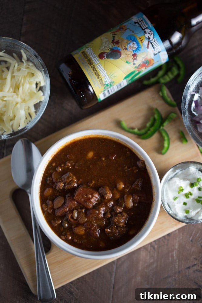 A rustic bowl of thick Stout Beer Chili with vibrant toppings, ready to be enjoyed.