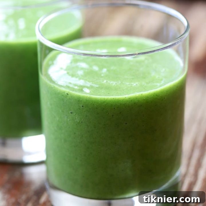 A vibrant Mango Pineapple Kale Smoothie in a glass, ready to be enjoyed. This healthy, paleo and Whole30 compliant smoothie is a delicious way to boost nutrients.