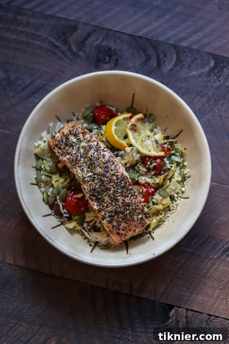 A beautifully presented Salmon Rice Bowl with a vibrant mix of ingredients and a fork ready to enjoy.