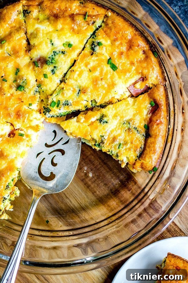 A generous slice of Low Carb Ham and Cheese Crustless Quiche, revealing a delicious filling of ham, cheese, and broccoli.