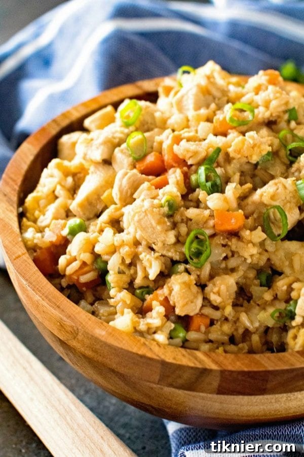 A large serving of Cauliflower Fried Rice with Chicken, garnished with green onions and sesame seeds, a healthy low-carb meal.