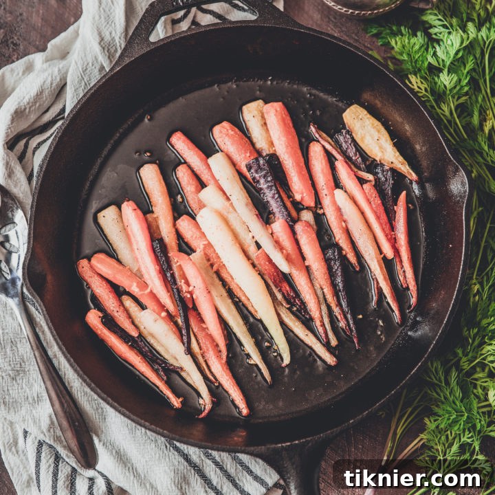 Close-up of golden-brown roasted rainbow carrots, sprinkled with orange zest, ready to serve.