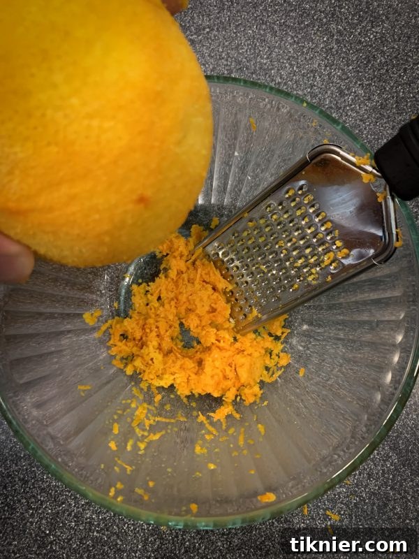Fresh orange zest being grated for cream cheese frosting.