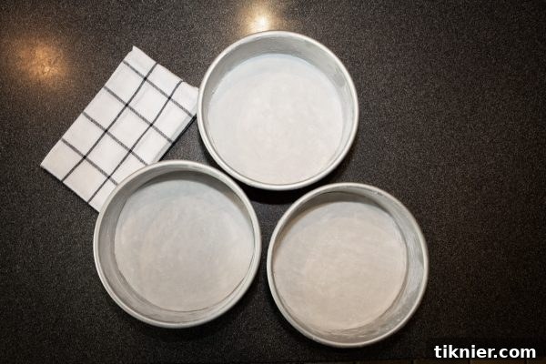 Cake pans prepared with shortening, flour, and parchment paper.