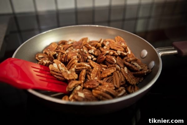Pecans toasting in a pan for enhanced flavor.