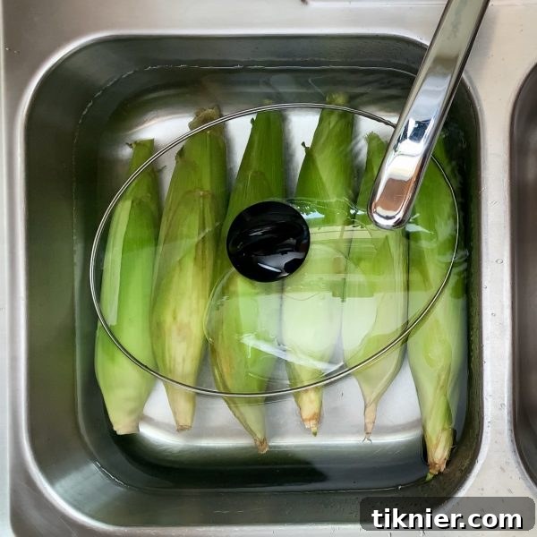 Use a lid to hold corn under water during soaking