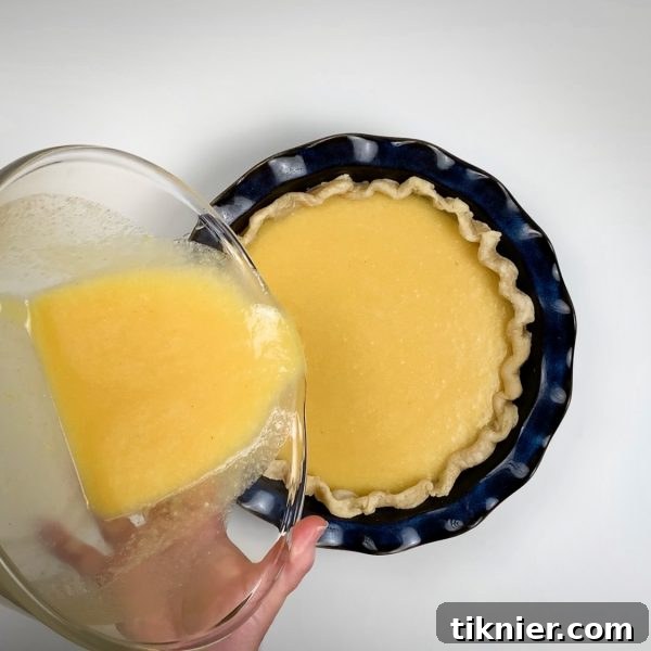 Irresistible Chess Pie 23 pouring chess pie filling into a partially baked pie crust