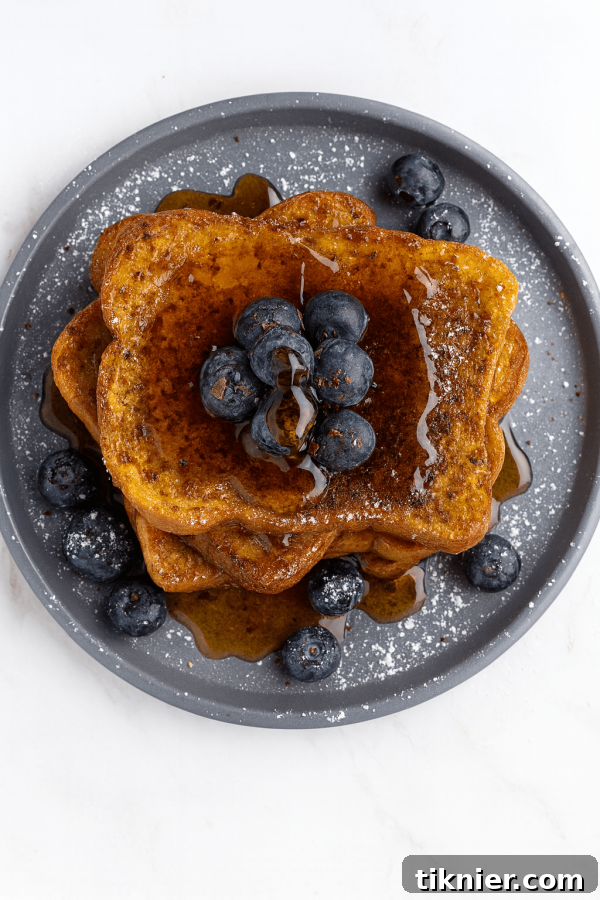 Delicious golden brown gluten-free French toast with powdered sugar and fresh berries on a plate