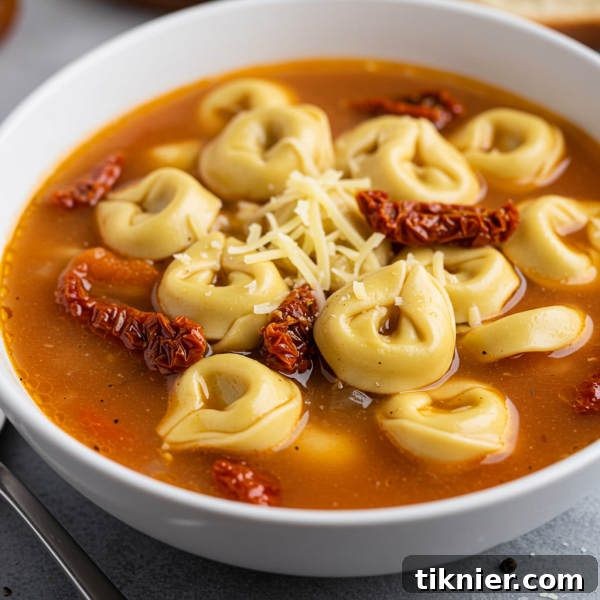 A deliciously creamy bowl of slow cooker tortellini soup garnished with fresh herbs.