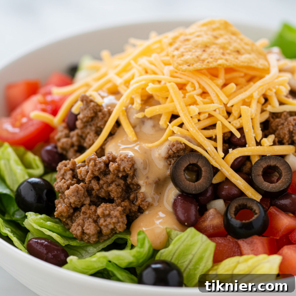 Delicious and vibrant taco salad with seasoned ground beef, fresh vegetables, and a zesty homemade Catalina dressing, topped with crushed Nacho Cheese Doritos.