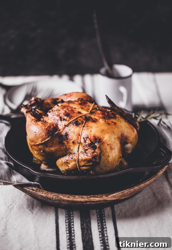 A beautifully roasted whole turkey, golden brown and garnished with herbs, on a platter, ready to be carved as the centerpiece of a Thanksgiving dinner.