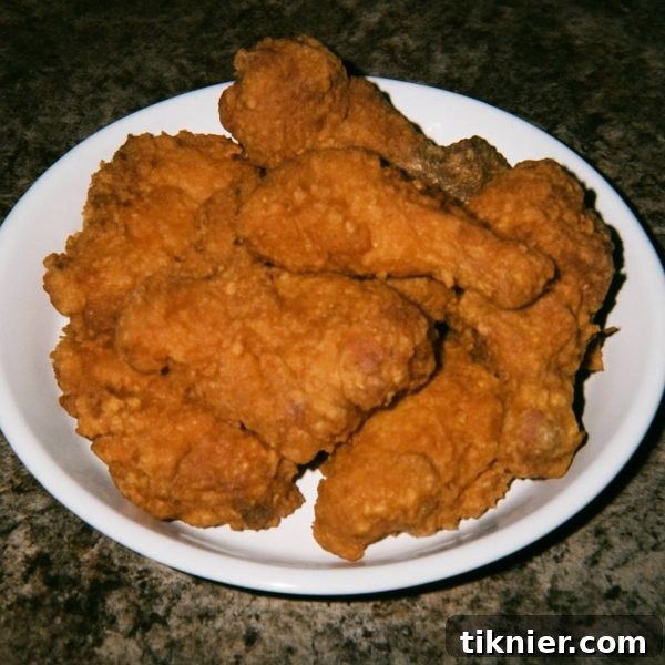 Golden-brown, crispy fried chicken pieces stacked on a platter, showcasing their delicious texture.