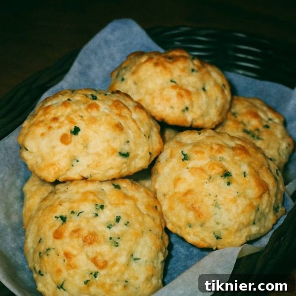 Warm, golden-brown Red Lobster Cheddar Bay Biscuits, fresh from the oven, drizzled with garlic herb butter, with a hint of steam rising, placed in a rustic basket on a wooden table.