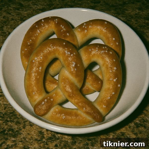 A plate of golden brown, salted Auntie Anne's style soft pretzels with a melted butter sheen, ready to be served.
