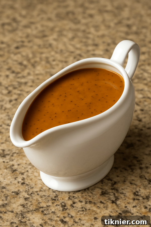 A gravy boat filled with smooth, rich Thanksgiving gravy, ready to be poured over dishes.