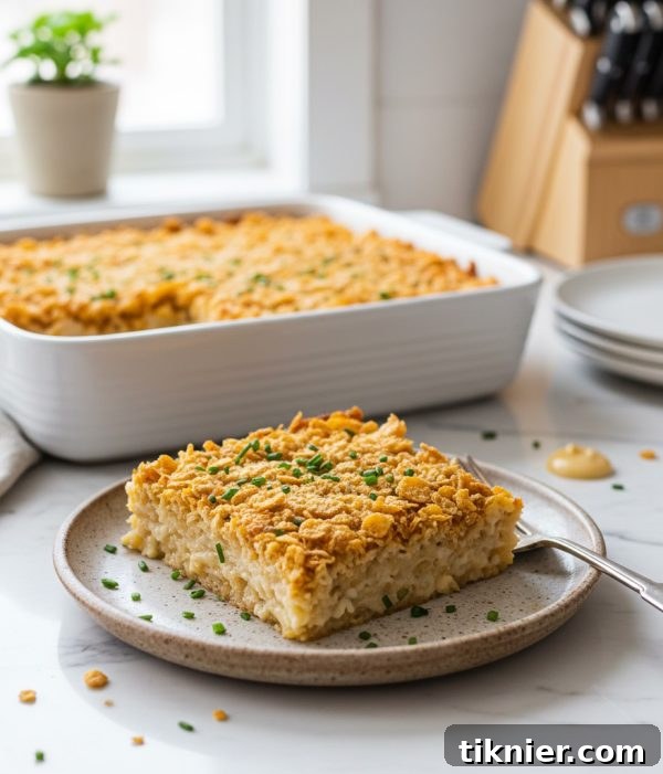 Gooey Cheesy Hashbrown Bake with a Golden Cornflake Crisp 2 Delicious Extra Cheesy French Onion Hashbrown Casserole baking in a dish, showing its golden-brown topping and creamy texture.