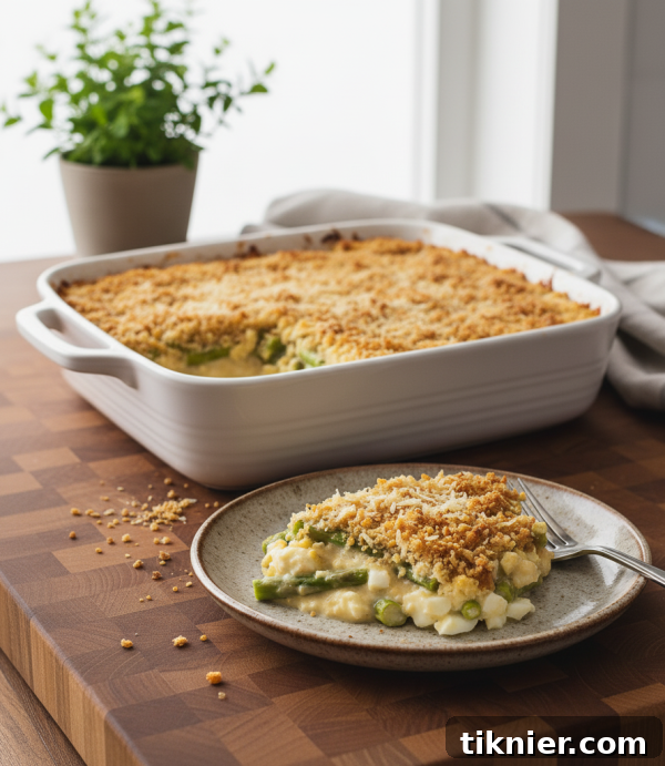 Creamy, cheesy old fashioned asparagus casserole with a golden brown panko topping, garnished with fresh dill.