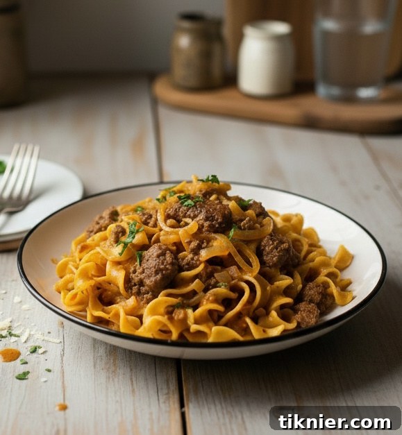 Close-up of creamy smoked Gouda ground beef and noodles in a skillet, garnished with fresh parsley.