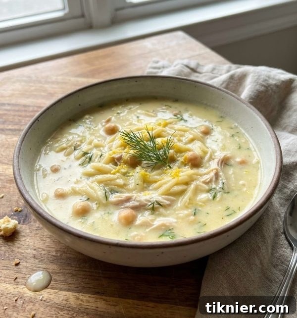A close-up shot of the creamy Greek lemon soup in a rustic bowl, garnished with fresh dill and a lemon slice.