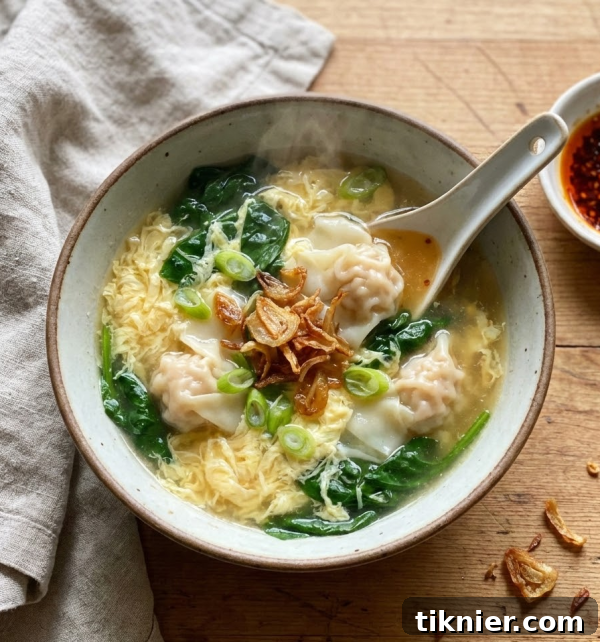 Close-up of Wonton Egg Drop Soup with crispy shallot and green onion garnish.