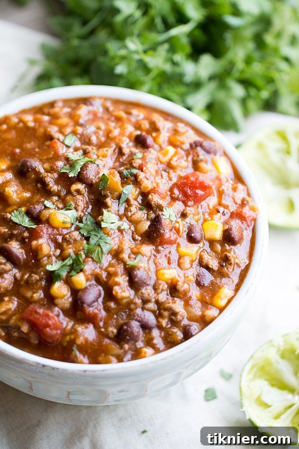 A vibrant bowl of hearty bean and lentil soup, garnished with fresh herbs.